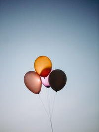 Low angle view of colorful balloons flying against clear sky