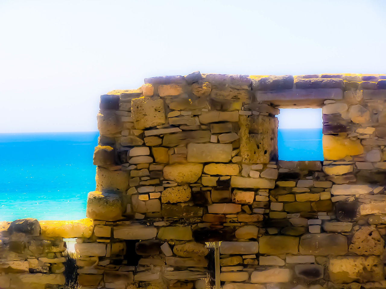 sea, architecture, built structure, horizon over water, building exterior, rock - object, stone wall, water, clear sky, history, blue, sky, old, rock formation, old ruin, the past, day, copy space, outdoors