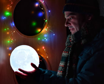 Man holding illuminated sphere at night