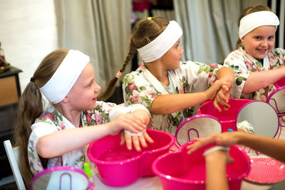 High angle view of girls cleaning hands with cotton pad in spa