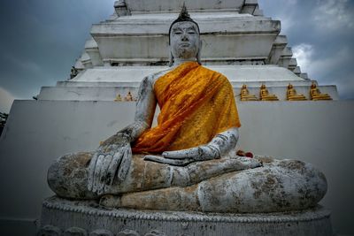 Statue of buddha outside building against sky