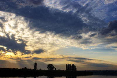 Silhouette trees against dramatic sky during sunset