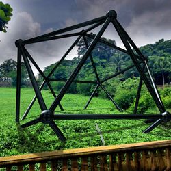 Close-up of metal fence on field against sky