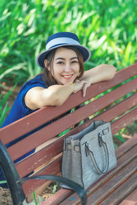 Portrait of young woman sitting on bench at park