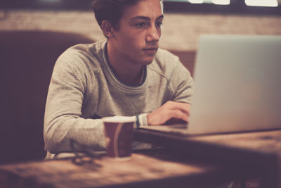 Young man using mobile phone while sitting on table