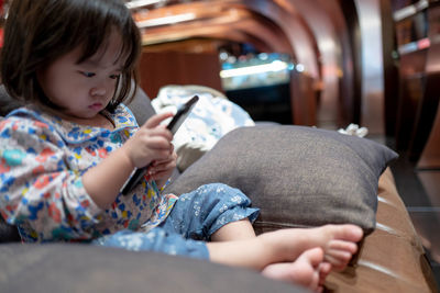 Baby girl using mobile phone while sitting at home