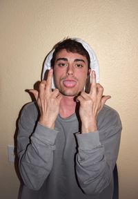 Portrait of young man showing middle fingers against wall
