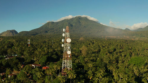 Telecommunication tower, communication antenna against mountains and rainforest, aerial view