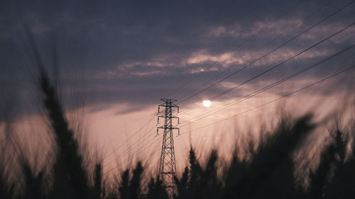 Low angle view of silhouette electricity pylon against sky at sunset