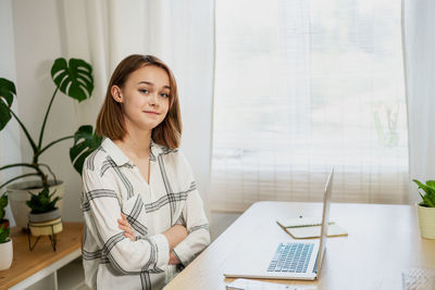 Young woman working on laptop at home. cozy home office workplace, remote work, e-learning concept.