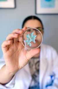 Portrait of female chemist technician showing blue glitter sample over petri dish on lab