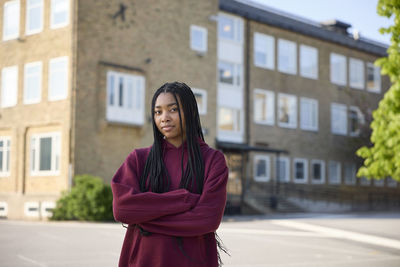 Smiling teenage girl with arms crossed looking at camera