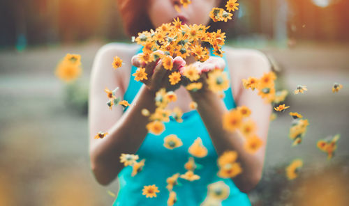 Midsection of woman blowing flowers