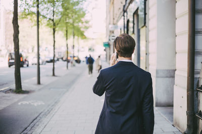 Rear view of businessman talking on phone in city