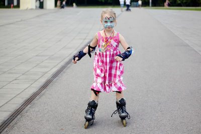 Portrait of cute girl inline skating on road 