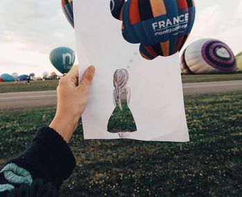 Low section of man on hot air balloons on field