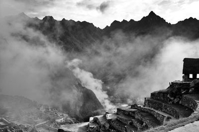Machu picchu by mountains during foggy weather