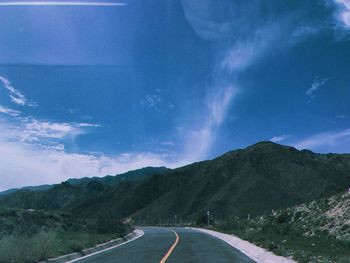 Empty road by mountains against sky