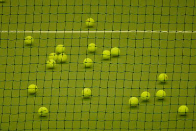 High angle view of tennis balls on court seen through net