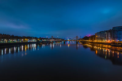 Illuminated bridge over river against sky at night