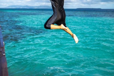 Low section of girl jumping in sea