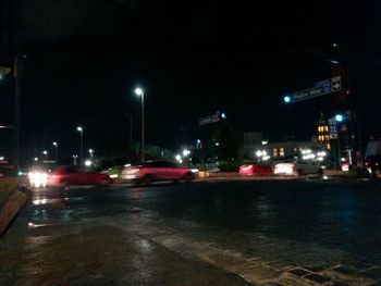 Cars on road by illuminated buildings in city at night