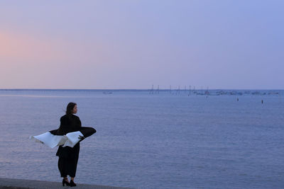 Rear view of man on beach against sky