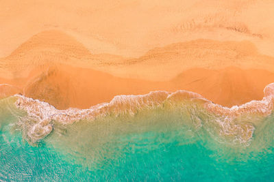 Aerial view of atlantic ocean coast with crystal clear turquoise water, waves rolling into the shore