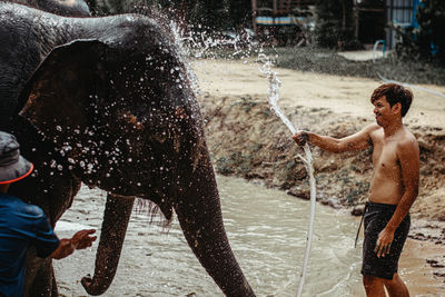 Young man splashing water in park