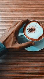 Cropped hand having coffee over table