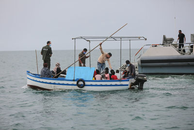 People on boat in sea against sky