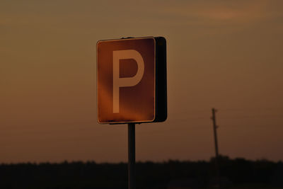 Close-up of road sign against sky during sunset
