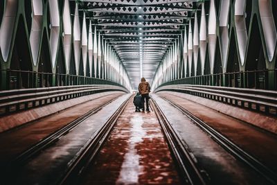 Rear view of man walking on railway bridge