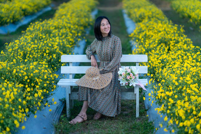 Portrait of smiling young woman standing on yellow flowering plants