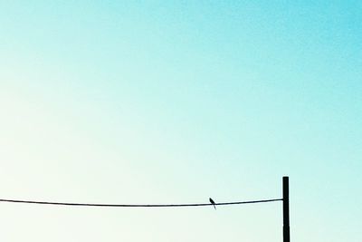 Low angle view of power lines against clear blue sky