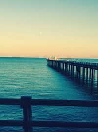 Pier over sea against clear sky during sunset