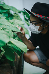 Young man wearing mask touching plant