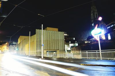 Light trails on road in city against sky at night