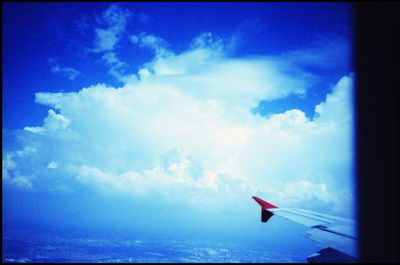 Airplane wing against cloudy sky