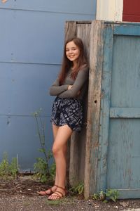 Portrait of woman leaning on cabin in yard