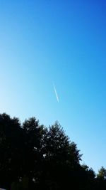 Low angle view of silhouette trees against clear blue sky