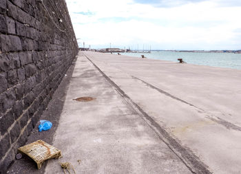 Empty road by sea against sky in city