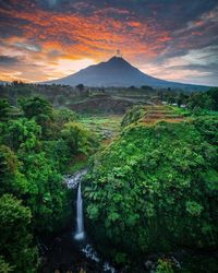 Scenic view of waterfall against sky during sunset