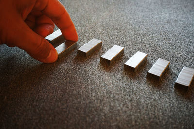 Cropped hand arranging stapler pins on table