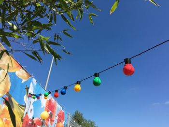 Low angle view of colorful balloons hanging against blue sky