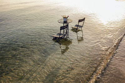 High angle view of chairs and table on sea