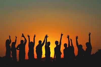 Silhouette people gesturing against sky during sunset