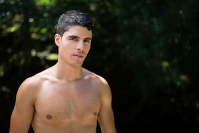 Portrait of shirtless young man standing outdoors