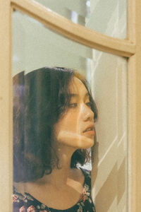 Close-up of young woman looking away through window