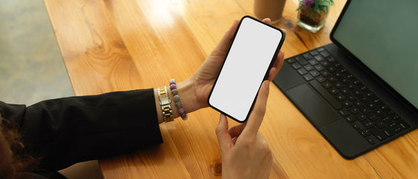 Midsection of woman using phone on table